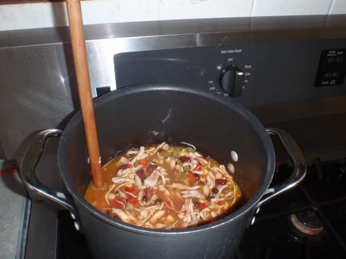 The broth, beans, corn, tomatoes and chicken simmer on the stove. Stir the chili occasionally.
