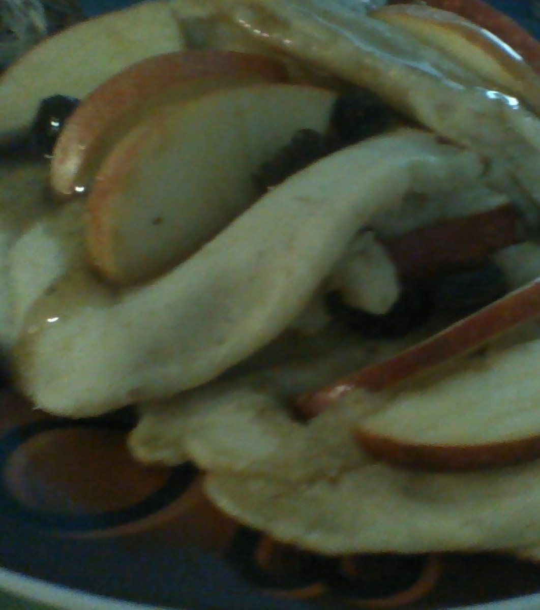 A plat of apple pancakes garnished with raisins and pure maple syrup