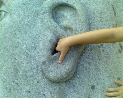 "Lend me your ear" - Small hand in the ear of the sculpture titled "Listening Stone" by Joseph Wheelwright
