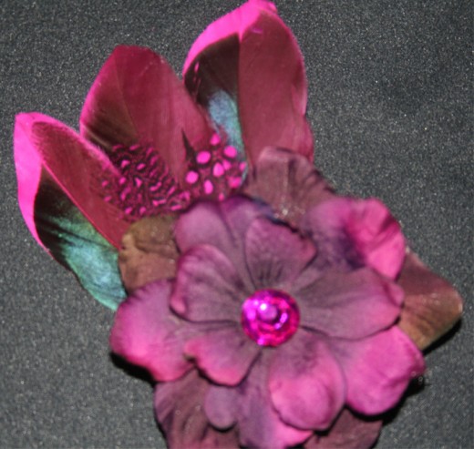 Purple flower hair clip with black and pink and black feathers, pink and black polka-dotted feathers, and two gems in the center.  This one was also given as a gift to a friend.