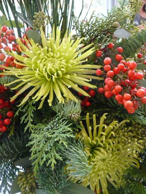 Select flowers that reflect the colors of Christmas. Seen here green mums, Christmas greens and red berries I stole from my friend's yard. 