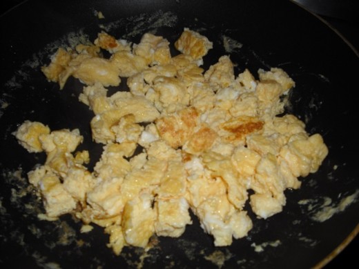 Now break that into smaller pieces with your spatula and add it to the fried rice in the wok.