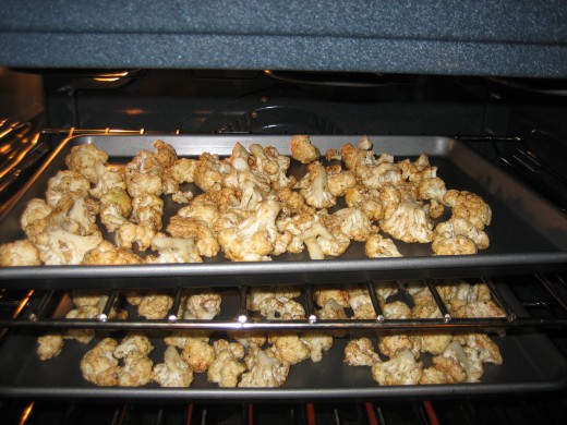 Two cookie sheets of cauliflower candy roasting in the oven.