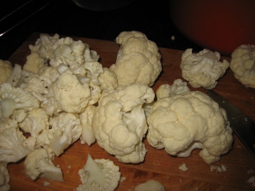 Cut the cauliflower head into florets before coating it in melted butter or oil, preparing it for the spice mixture.