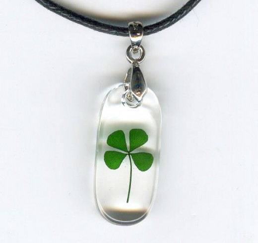 This beautiful Celtic necklace contains a genuine four leaf clover frozen in clear acrylic polyresin suspended on a black cord necklace. Pendant is about the size of a dime.