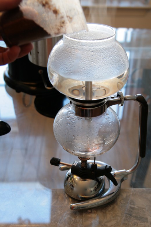 Add the freshly ground coffee beans into the top of the siphon brewer.  I grind the beans, while the water is rising, about the same coarseness as you would use in a drip brewer. 