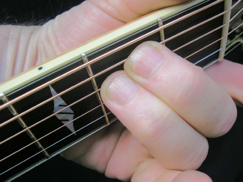 Em chord being fingered on the guitar