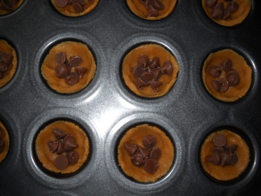 Peanut butter cookies with milk chocolate in the center before the top layer is put in place.