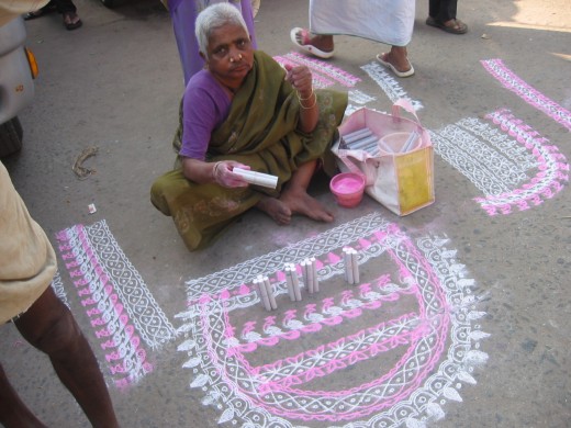 The ladies draw chalk designs outside their houses