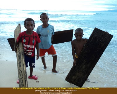 Papuan children with very simple wooden surf boards