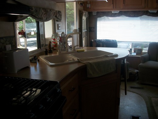 Rear lounge layout - a large picture window at the end of the RV and two overstuffed rocking chairs separated by an end table.