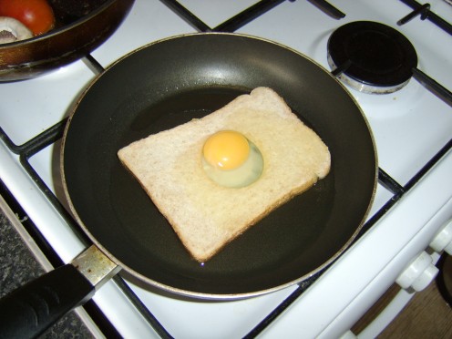 Egg is carefully poured on top of bread to ensure yolk slips in to the hole