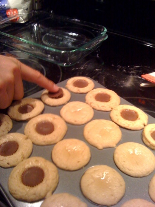 When the cookies are partially baked, remove the pan and gently press a Reese's miniature peanut butter into the center of the cookie. Return the pan to the oven.
