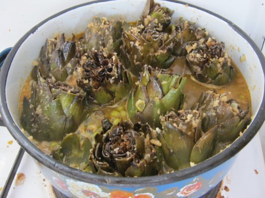 Artichokes are cooked on the stove with peas or lima beans after being stuffed with a breadcrumb, olive oil, garlic and parsley mixture.  Bon Appetit!