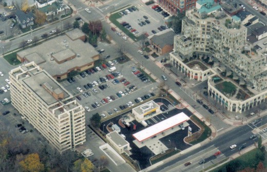 The site of the future parking garage on Locust St. (2001) before construction began when it was still a parking lot. Also the former Halton Regional Police Building can be seen to the left of the parking lot.