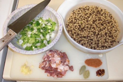 Here are the ingredients for this delicious dish!  Shown here are chopped onion, celery, green bell pepper and garlic.  Also chopped country style bacon, whole bay leaves, red pepper flakes, creole seasoning and dried blackeyed peas (soaked in water)
