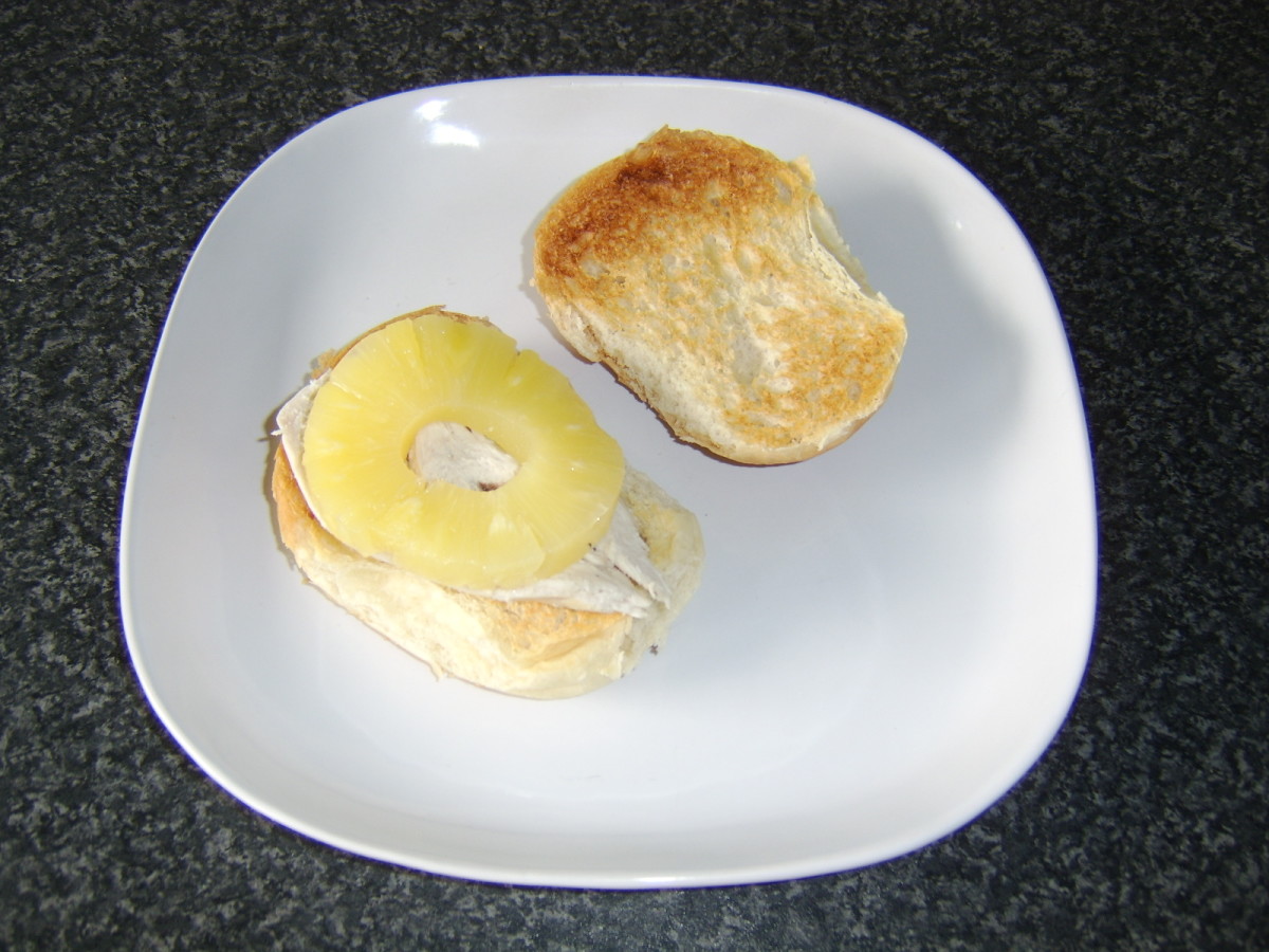 The chicken breast is halved and placed on one half of the roll with the pineapple ring