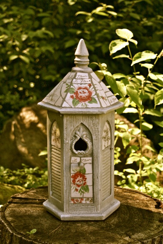 A birdhouse sitting on a short tree stump.