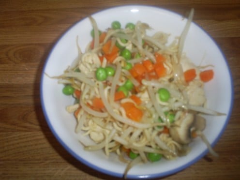 The finished chicken stirfry that contains ichiban noodles, bean sprouts, carrots, and peas.