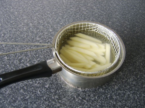 Potatoes for French fries are parboiled in a wire basket to make for ease of removal from the pot and drainage