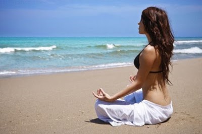 A woman meditates by the sea. Meditation can be used as effective pain relief for Rheumatoid Arthritis 