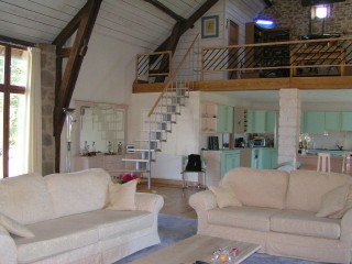 The same barn as above showing the interior converted.  A spectacular vaulted room with mezzanine, retaining all the original beams and some stone walls. Window to front. contemporary open style staircase to mezzanine & cloakroom. Solid pine floor an