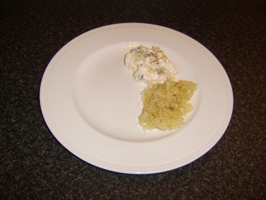 Potato salad and sauerkraut are added to the serving plate and garnished with an optional scattering of freshly chopped dill
