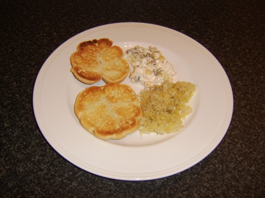 Toasted bread roll halves are added to the plate, cut side uppermost