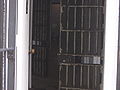 A view of the door to a maximum security cell in the Old Montana Prison, displaying the screen on the outside of the bars to protect guards from the sloshing of the "honey bucket"