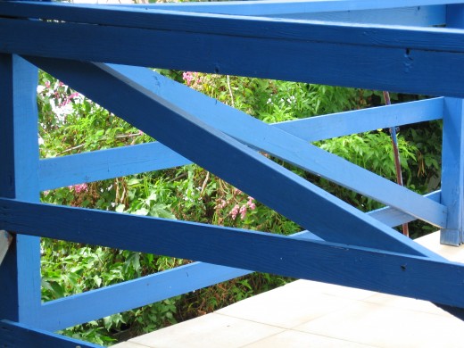 Blue painted fence in bright sunshine.