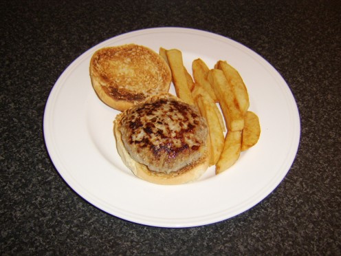 The pork and apple burger is laid on the bottom half of the toasted bap