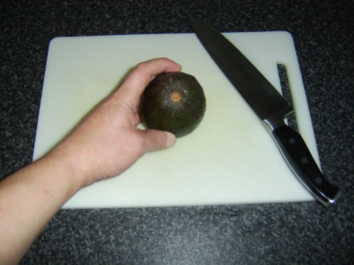 Hold the avocado broad end down on a chopping board