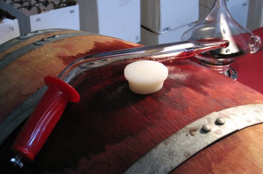 A glass wine thief lying on a wine barrel