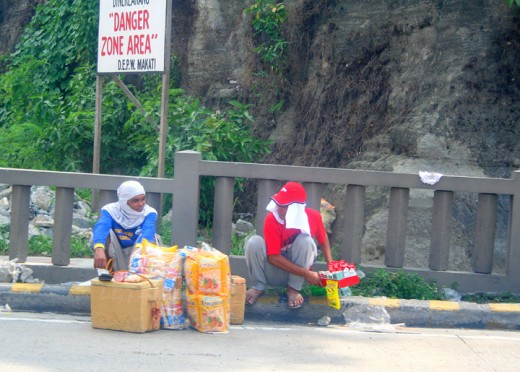 street hawkers taking a rest, unmindful of the danger sign behind them