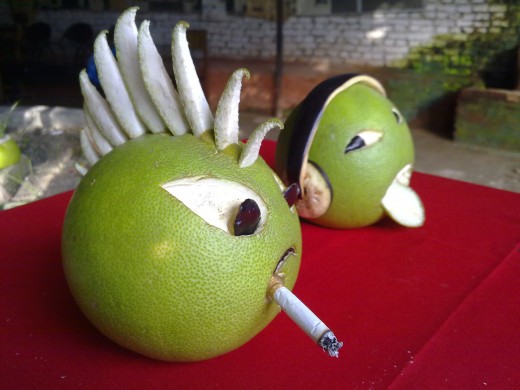 A cigarette on his lips a jerk is bothering a girl. Unripe pomelos are carved to create this interesting art.