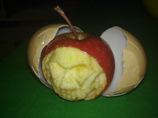 An apple with a face of a man is hatched out of an egg.