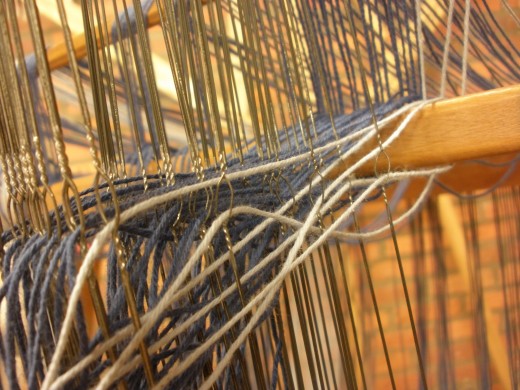 Threading the heddles in preparation for weaving.