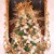 Elegant gold themed tree was displayed on a mahogany table with guilded mirror behind it. Elegant gold themed tree was displayed on a mahogany table with guilded mirror behind it.