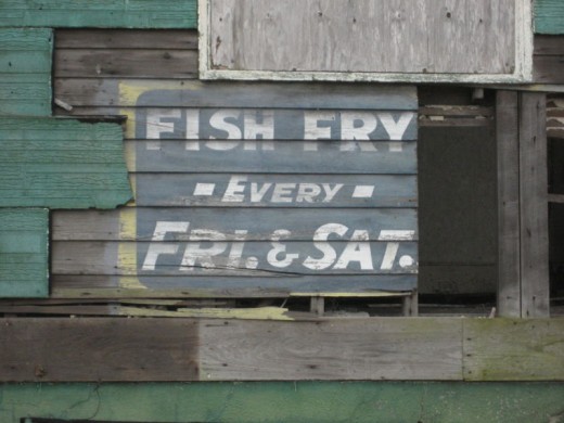 Weathered old sign on side of building Uptown, advertising "Fish Fry" held every Friday and Saturday.