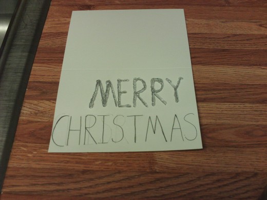 Here I am tracing over the "Merry" text with a silver glitter glue.