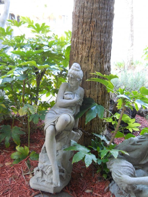 Photo of a statue by a pond with water fountains. 