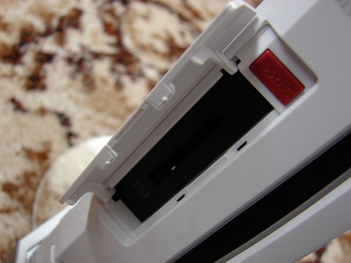 The Sync button on the Nintendo Wii is located inside of a compartment on the front of the console.