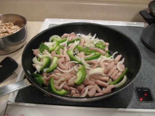 Add pepper and onion to browned pork strips.