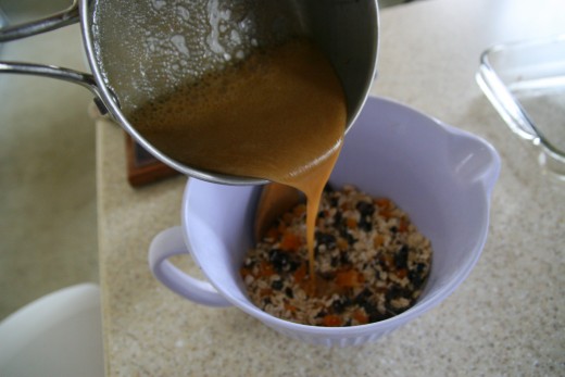 An adult should pour the hot honey mixture into the bowl of oats, prunes, and apricots.