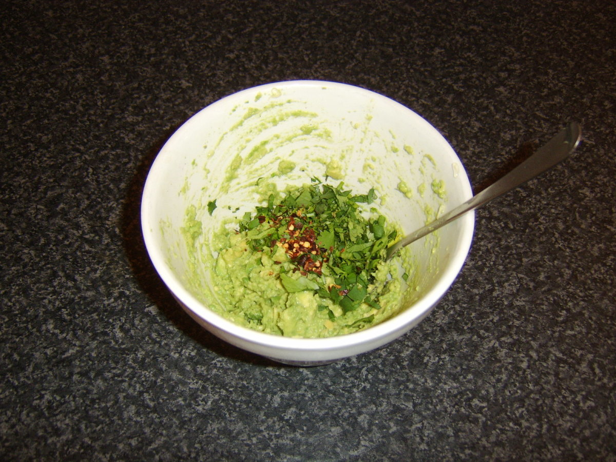 Herbs and spices are added to mashed avocado