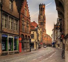 Tall and narrow buildings neatly lined up to the street are typical in the older sections of historical Belgium.  Some are triangle topped, others have a crown to signify the royal government.  Rain or shine, bicycles are a popular form of transport