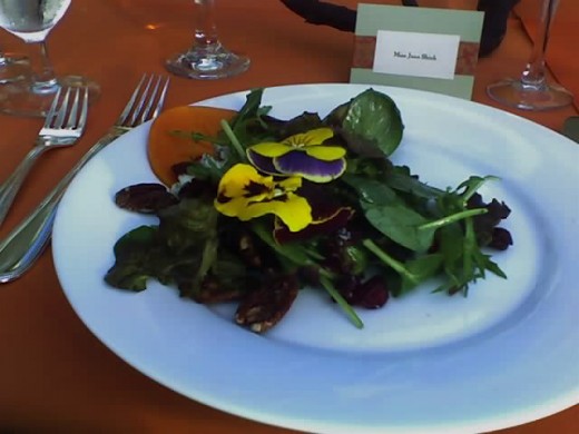 Salad with candied walnuts, persimmon slice, cheese, dried cranberries and pansies.