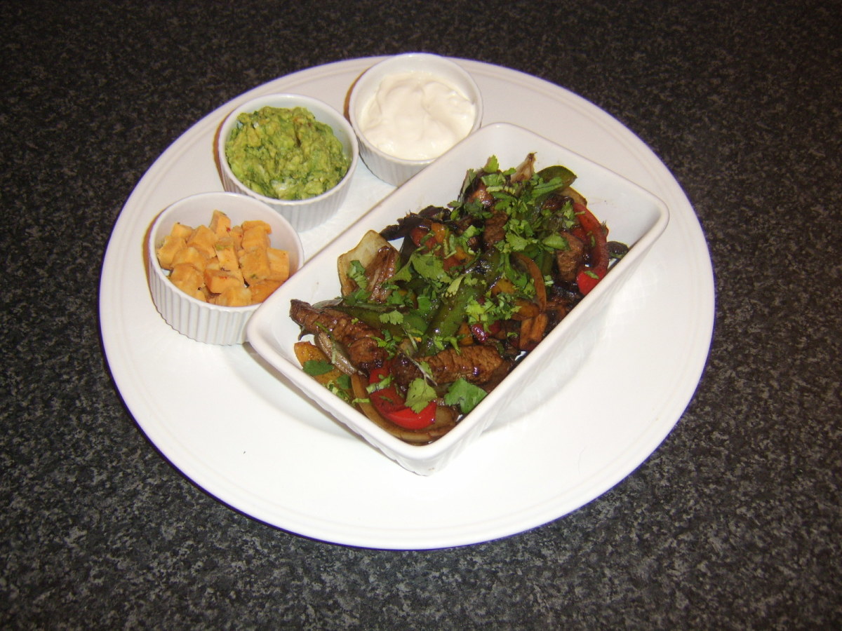 Stir fried steak, peppers and onions is accompanied by homemade guacamole, soured cream and Mexicana cheese, ready to be rolled in tortilla wraps