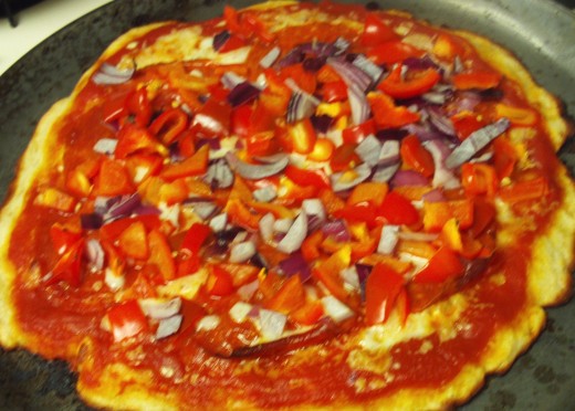 A homemade pizza topped with red bell peppers, purple onions, and pepperoni.