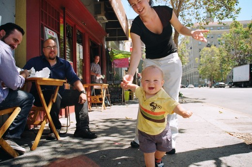 Walking holding onto one hand around 11 months - having never crawled an inch in his life.